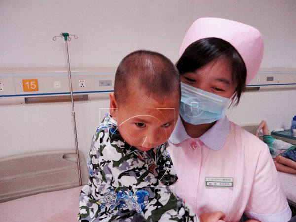 Longlong sits in the arms of the nurse. He is not so much nervous as before since he has been visited by many loving people and now is able to greet them sometimes.